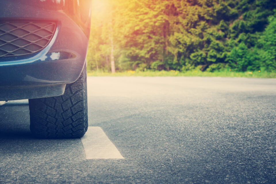 Osobné auto s letnými pneumatikami v horúčavách jazdiace po rozpálenom asfalte.